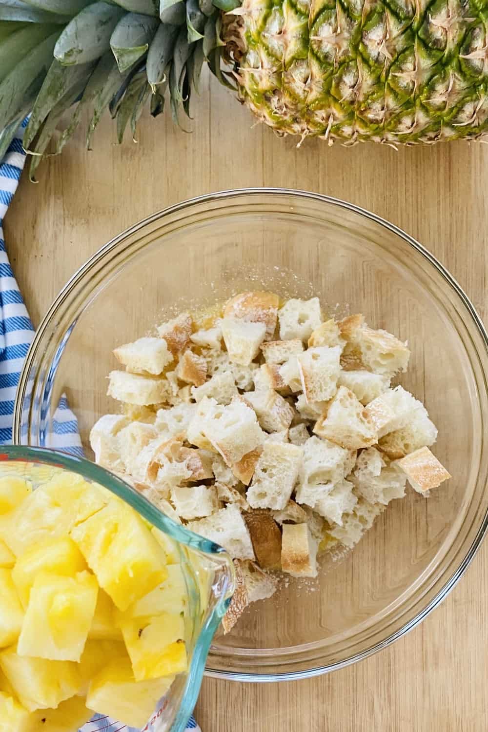 Combining fresh pineapple cubes with seasoned bread cubes.
