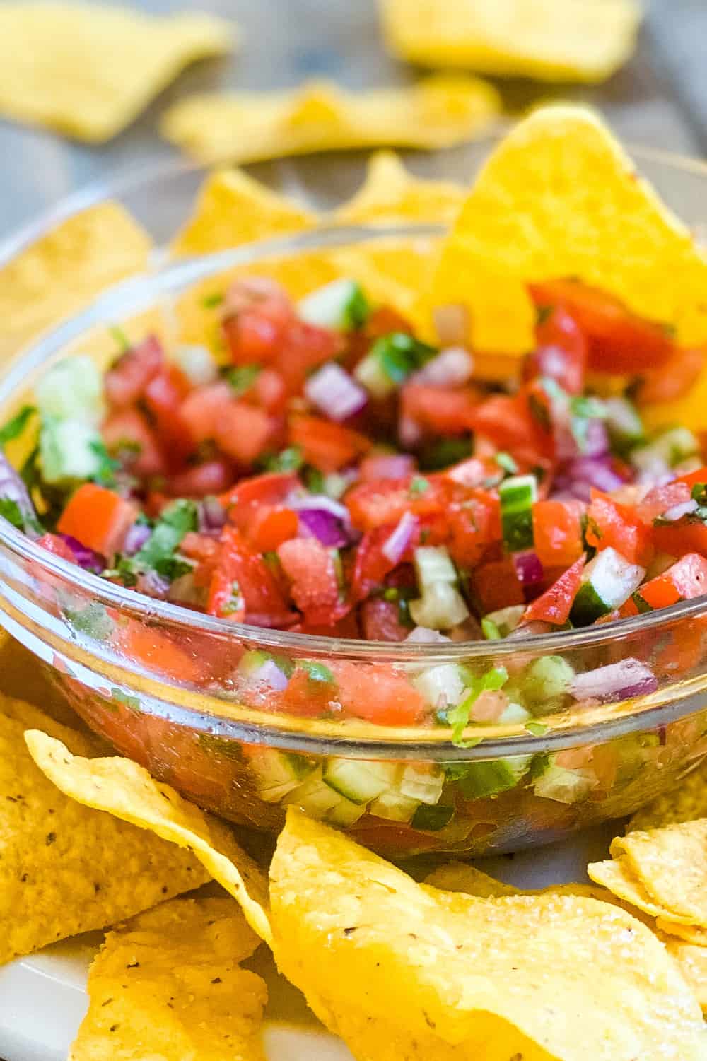 Pico de Gallo without jalapenos in a glass bowl with tortilla chips.