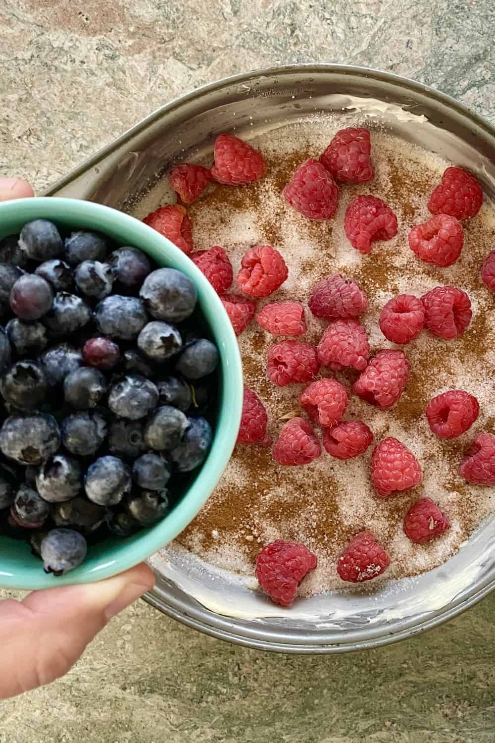 adding blueberries to berry upside down cake pan