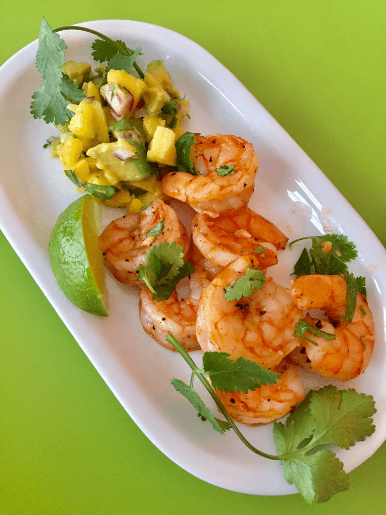 A small platter with chili lime tequila shrimp and lime slices.