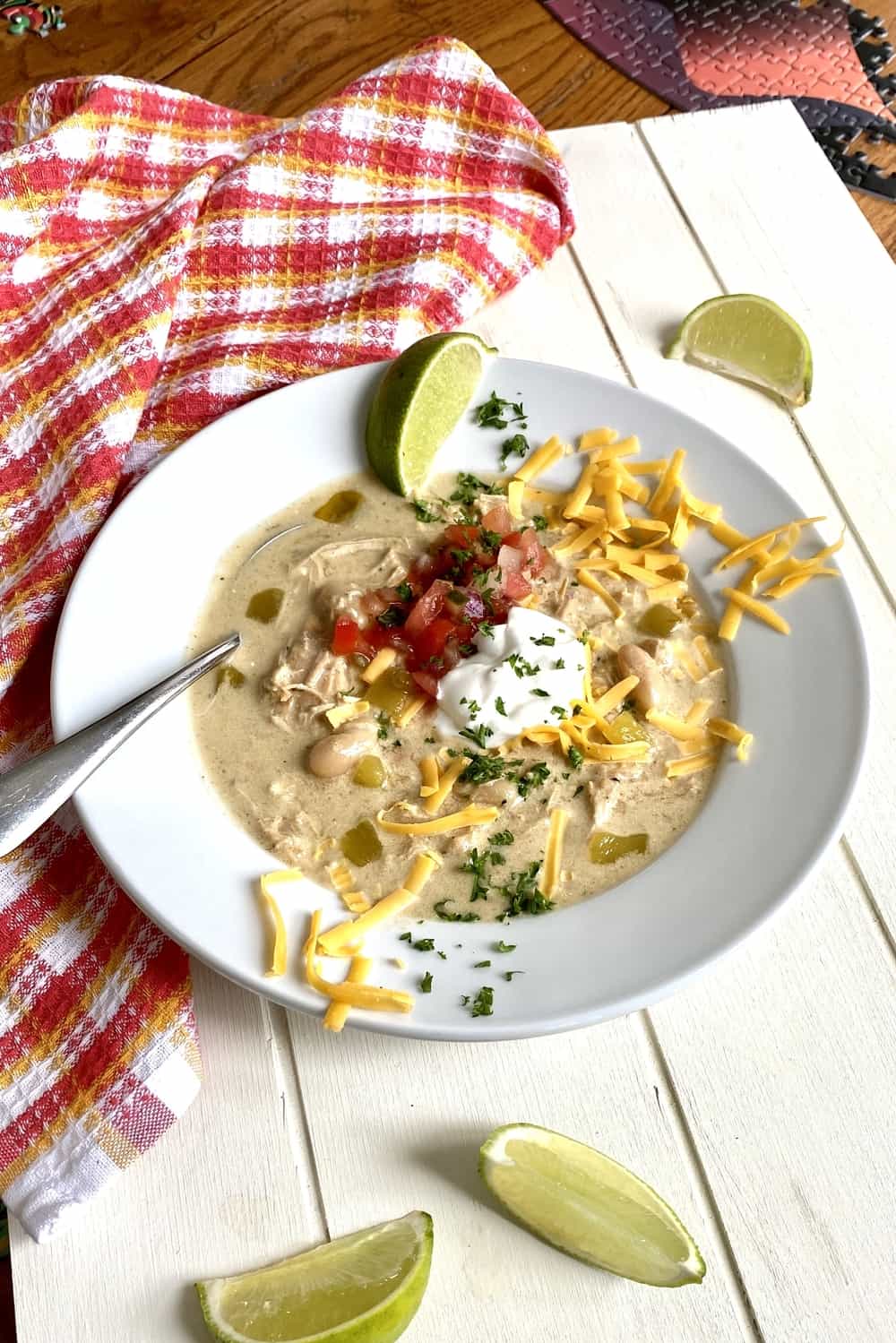 A bowl of creamy chicken enchilada soup with cheese and limes.