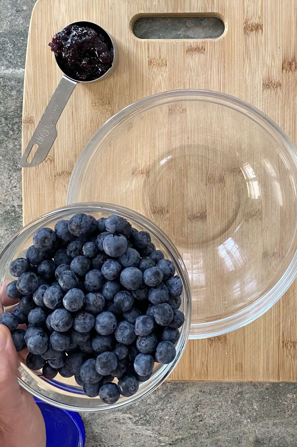 A bowl of fresh blueberries and some blueberry jam.