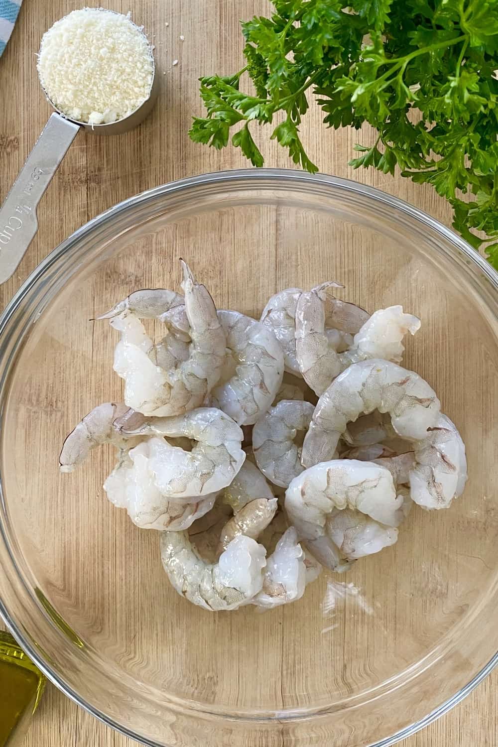 Raw shrimp in a bowl on a cutting board.