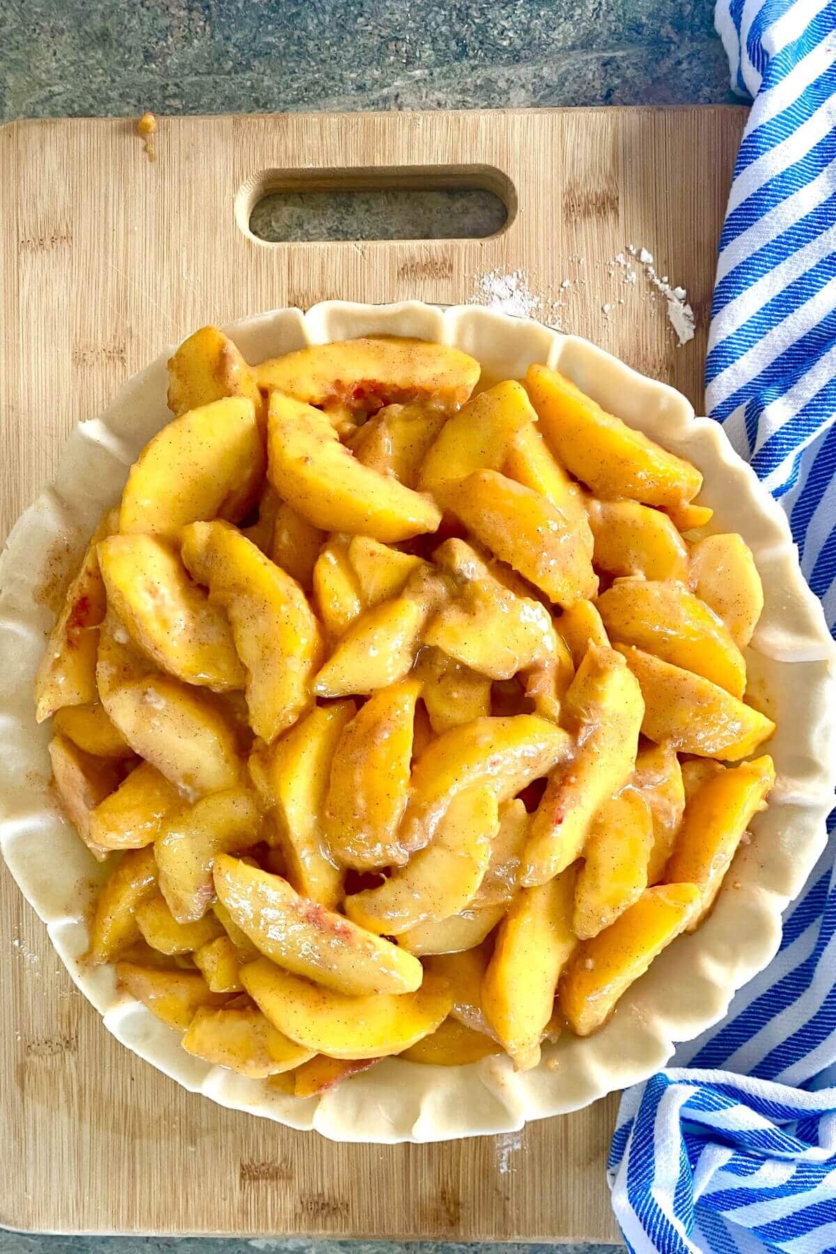 A filled peach pie and unbaked.