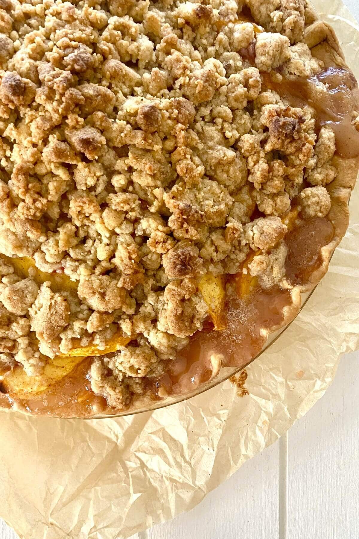 A baked peach pie on parchment paper.