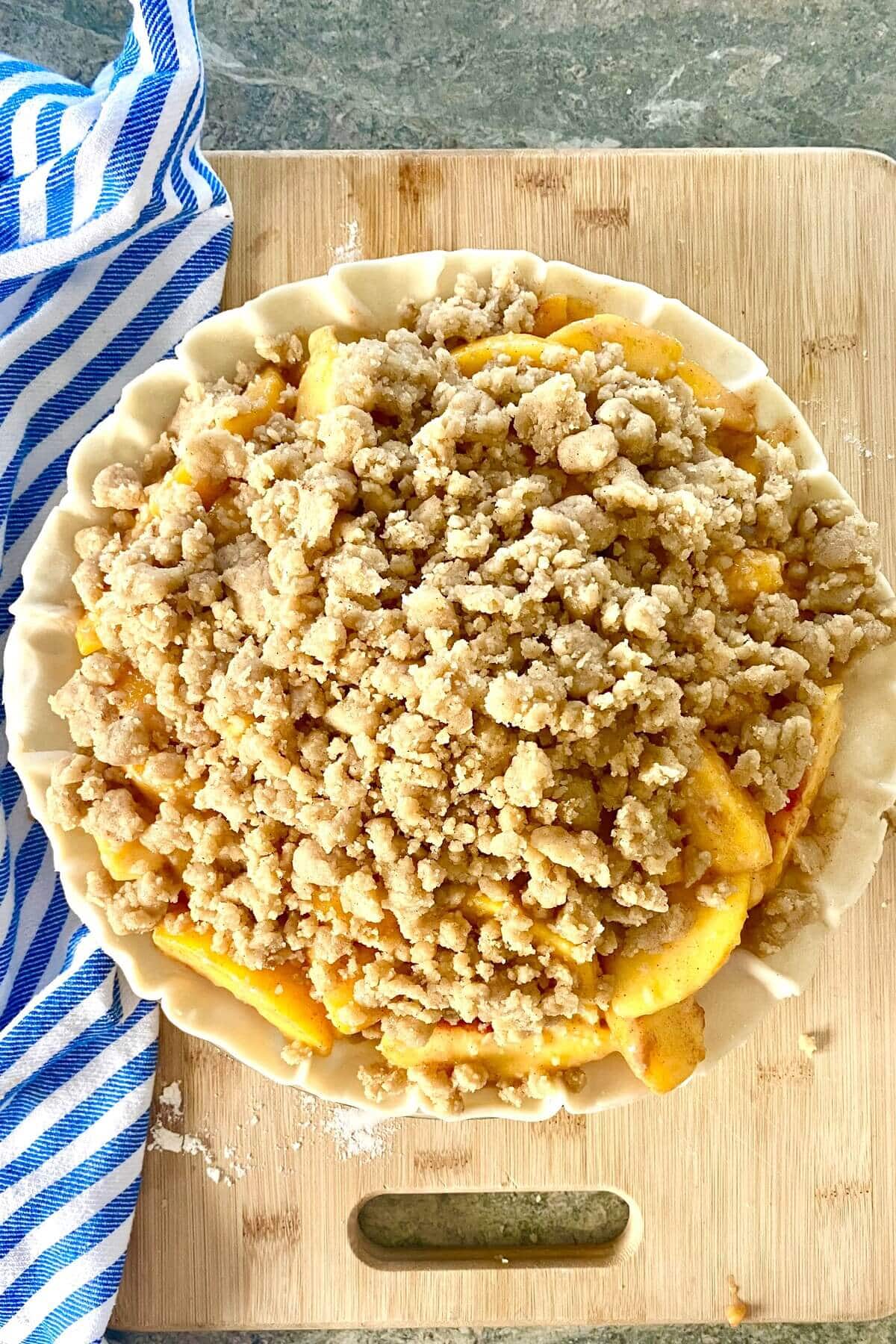 An unbaked peach crumble pie.