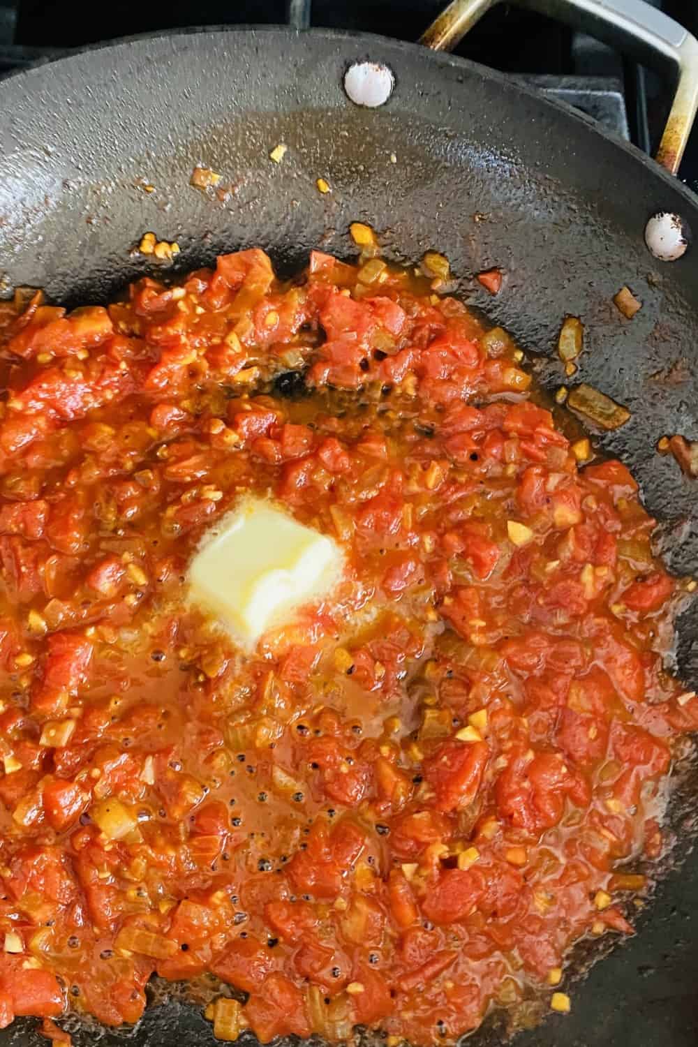 adding butter to tomato pan sauce