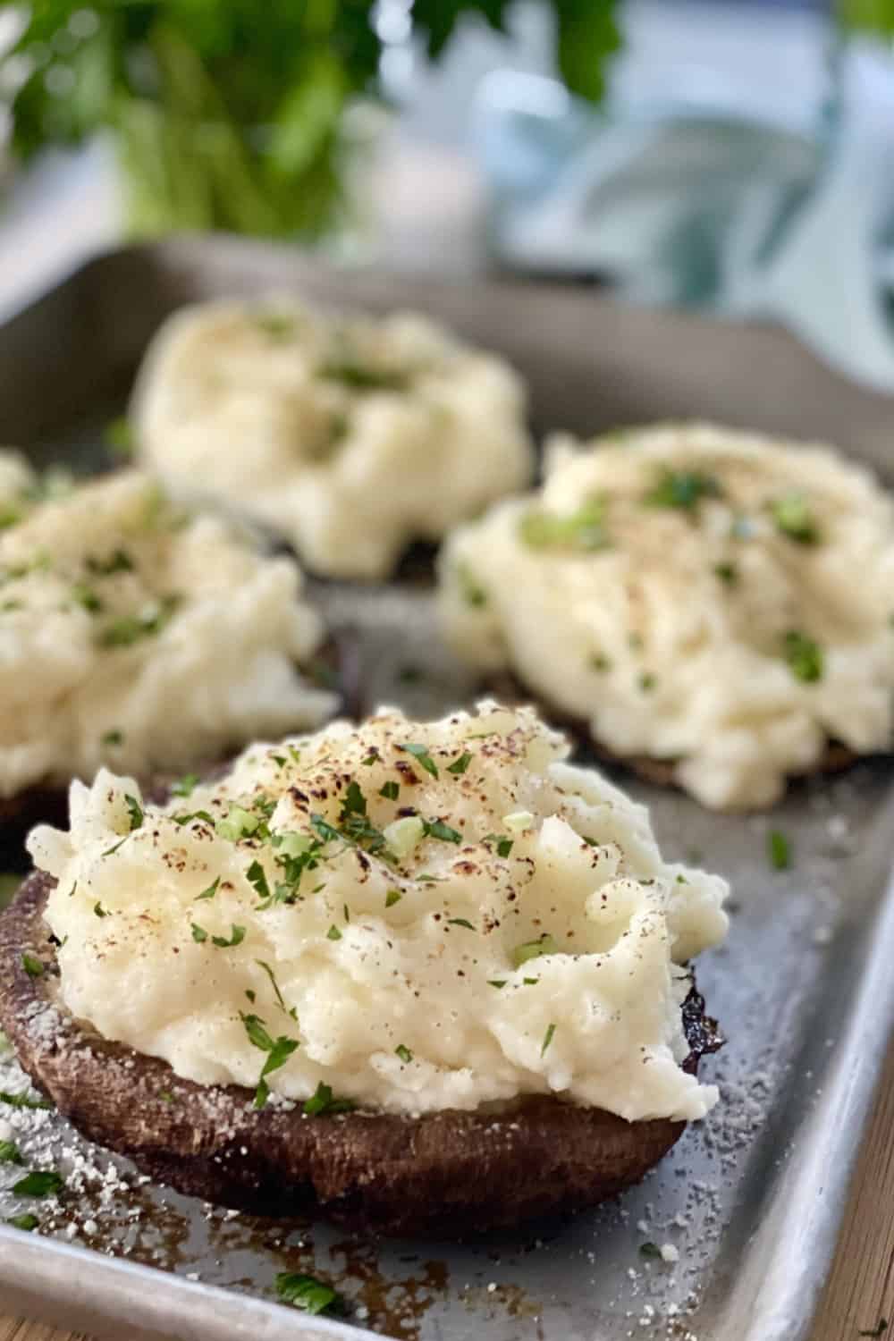 Large mashed potato stuffed mushrooms on a baking sheet.