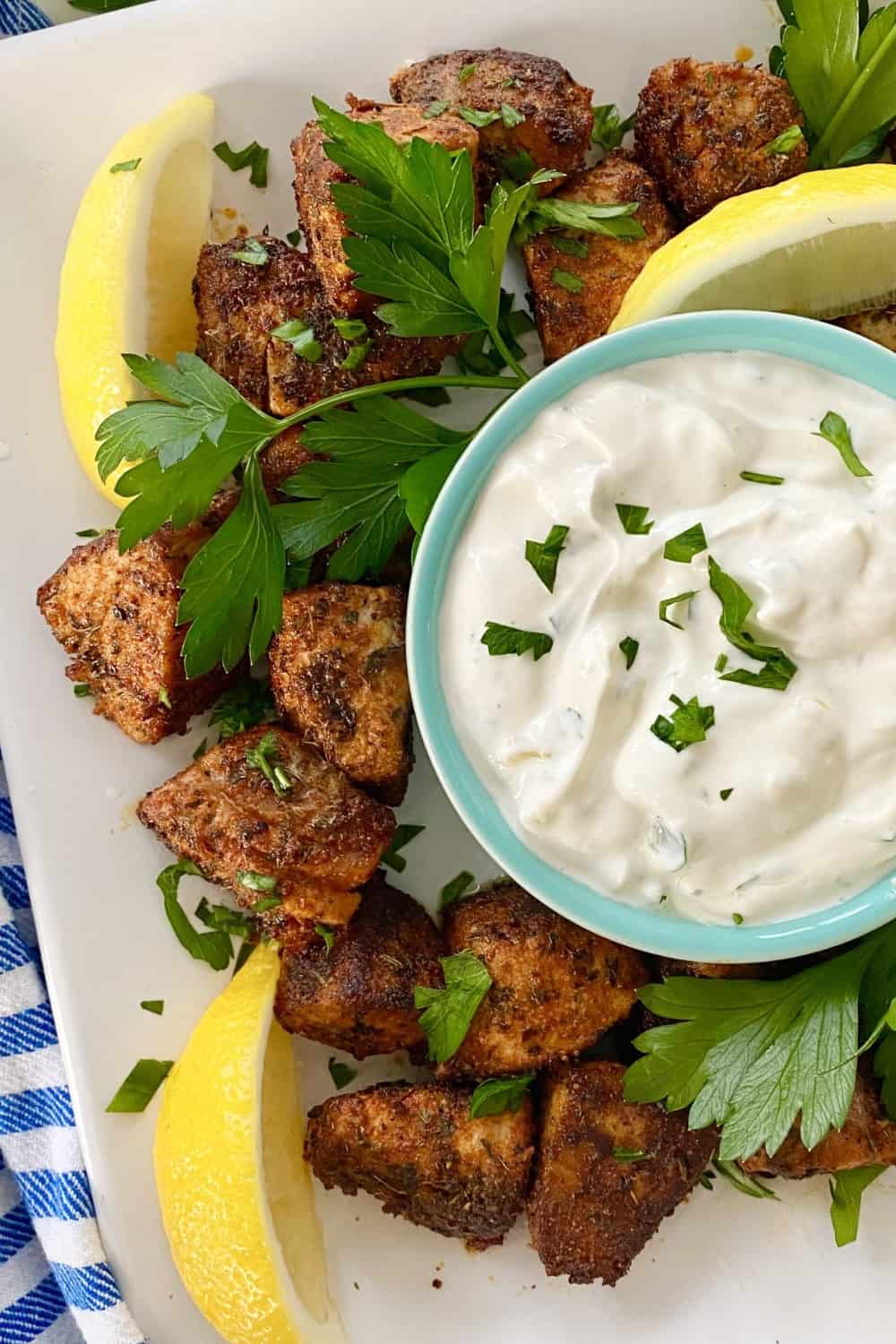Tuna bites with dipping sauce and lemon wedges.