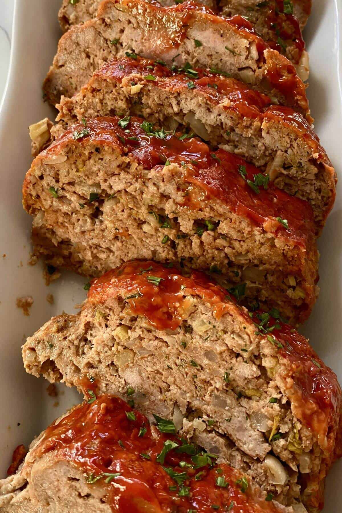 Slices of mom's meatloaf in a white serving dish.