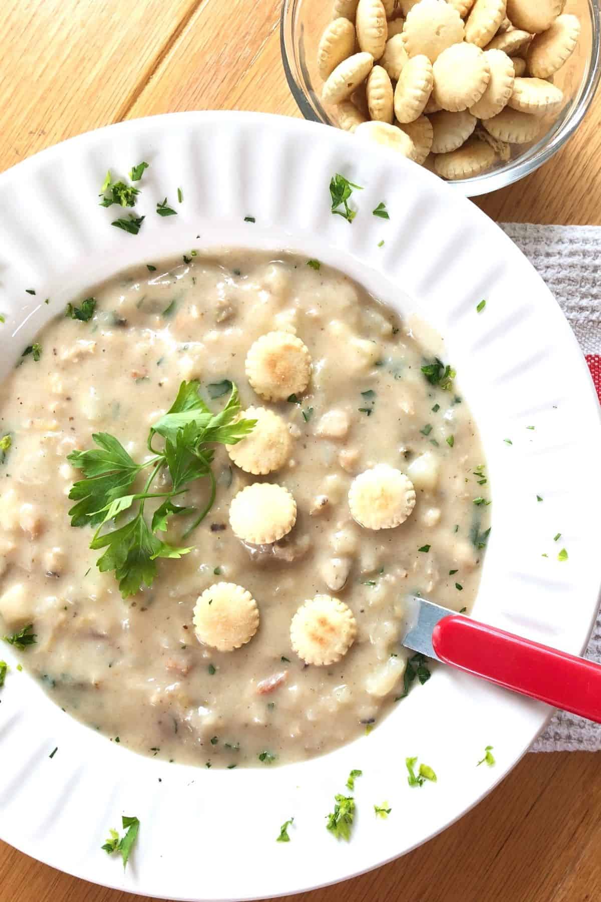 bowl of creamy New England clam chowder with oyster crackers.