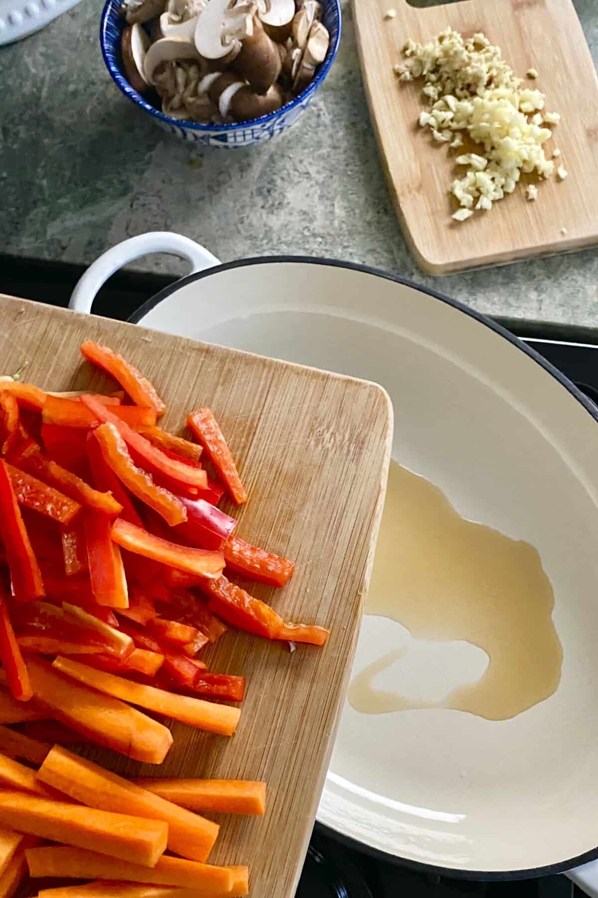 adding carrots and red peppers to sauté pan.