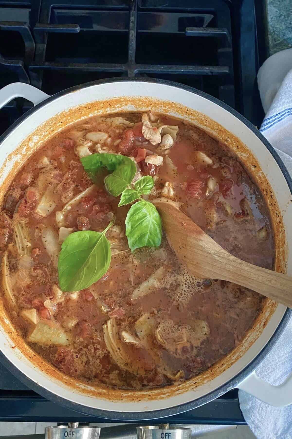A simmering pot of chicken soup with artichoke hearts.