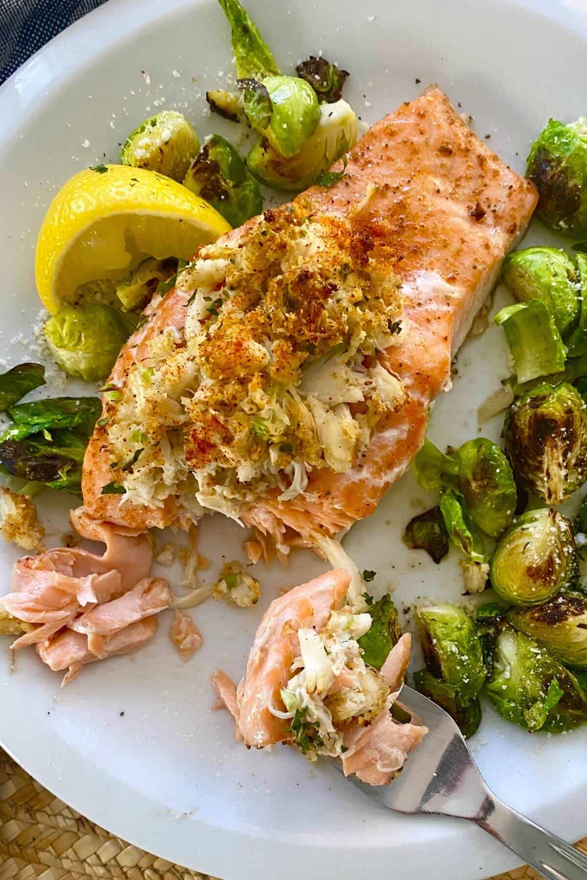 baked crab stuffed salmon with a bite on a fork.