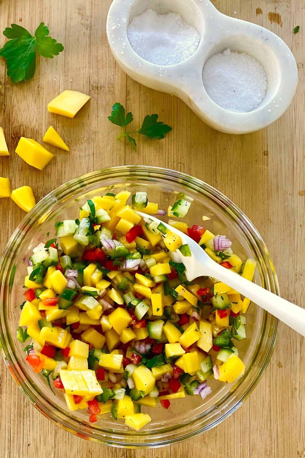 A mango salsa in a bowl with a spoon.