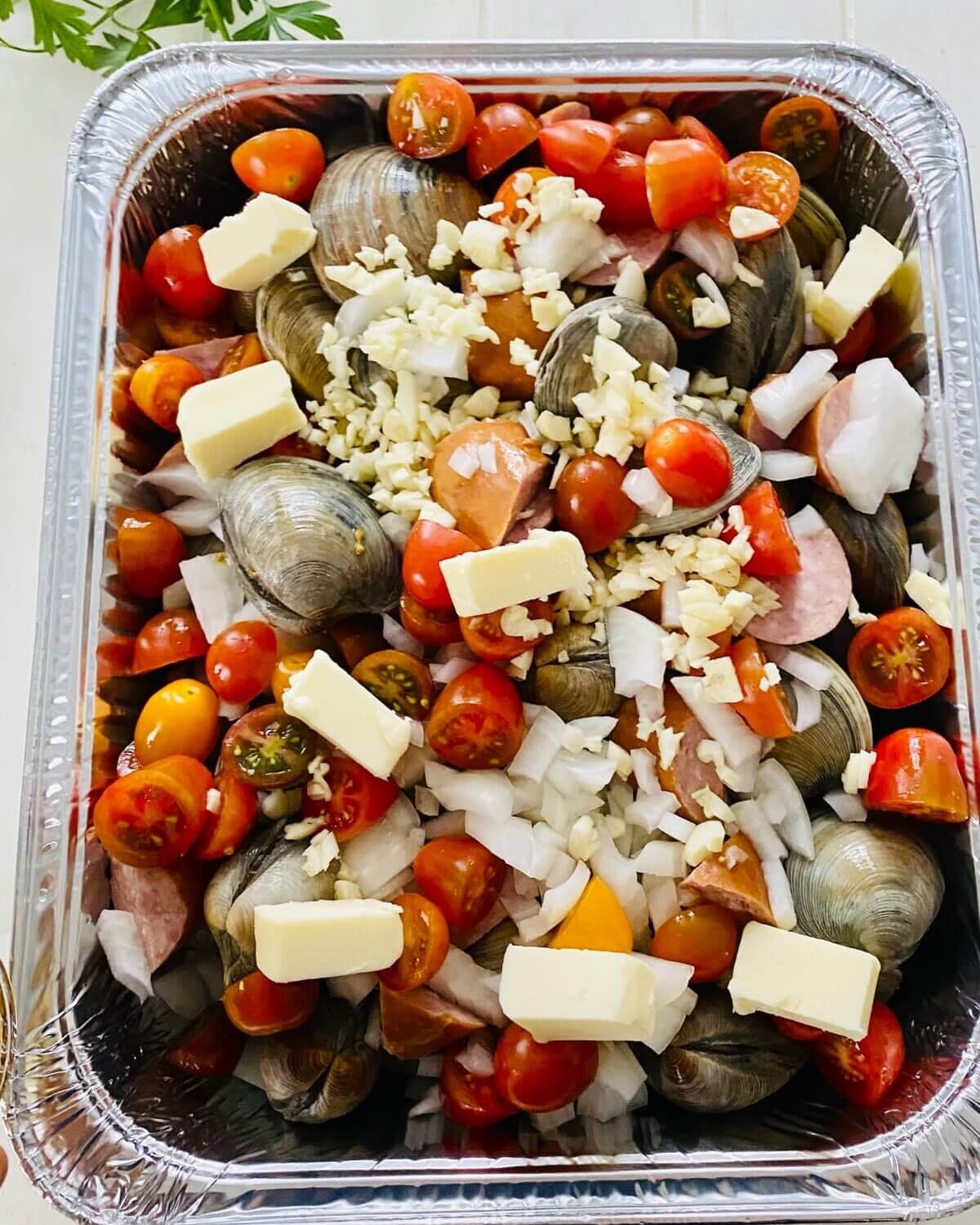 clams, kielbasa, butter, onion, garlic, tomatoes in a foil pan.
