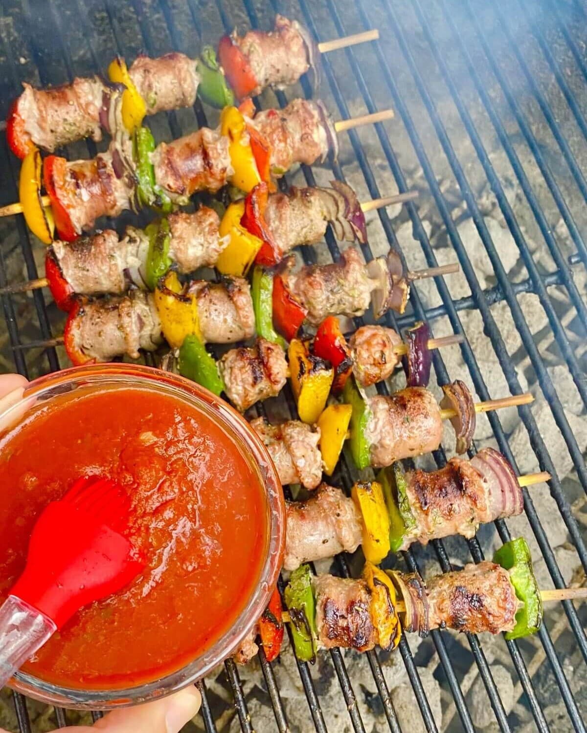 Brushing skewers with marinara.