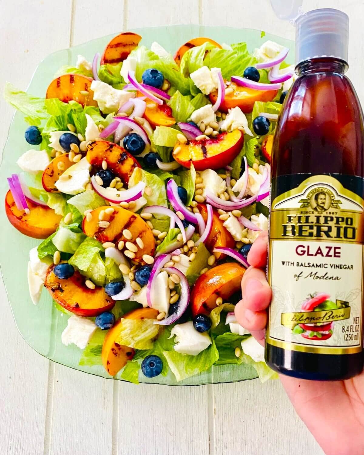 adding balsamic glaze to grilled peach salad.