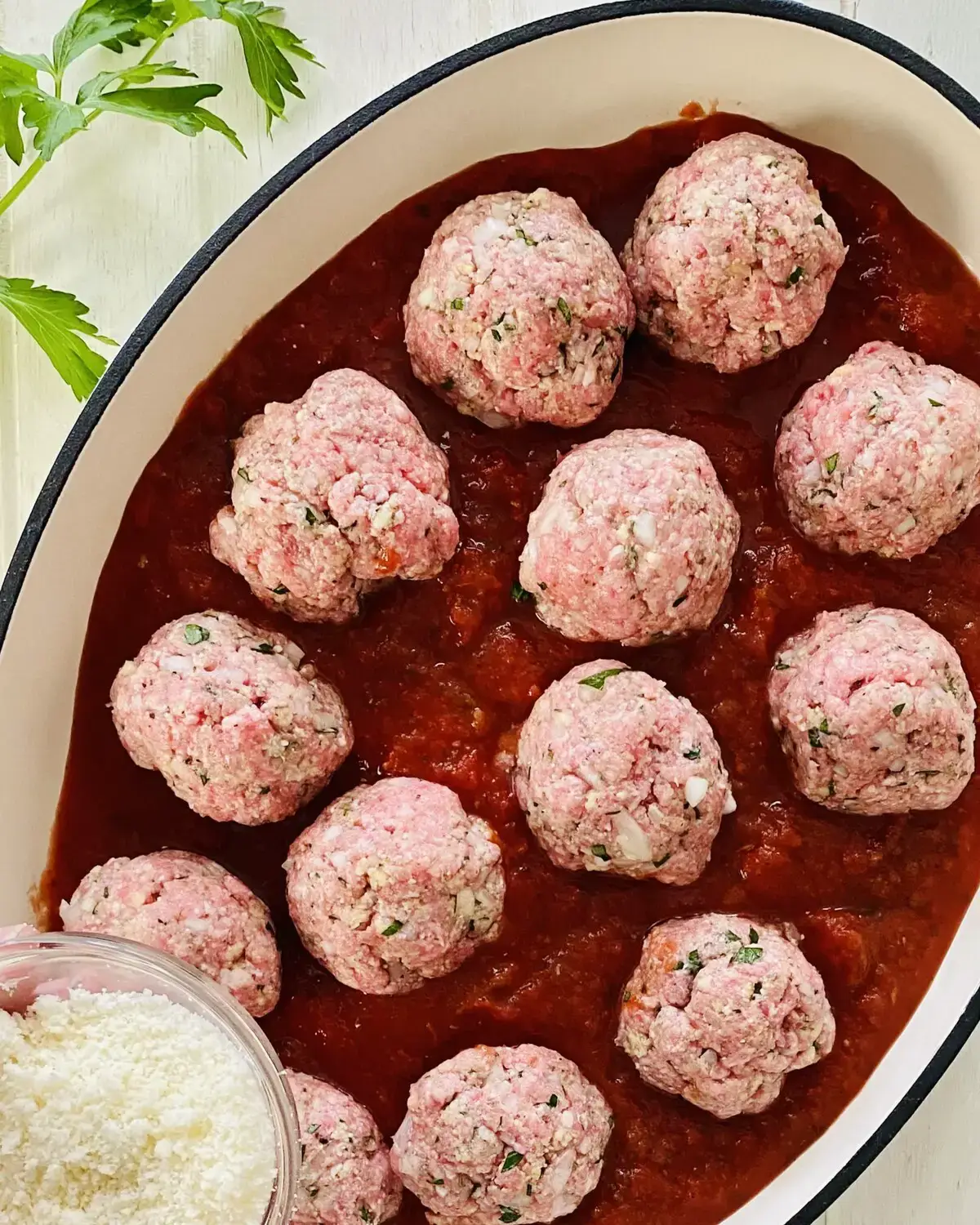 raw Italian meatballs in marinara sauce.