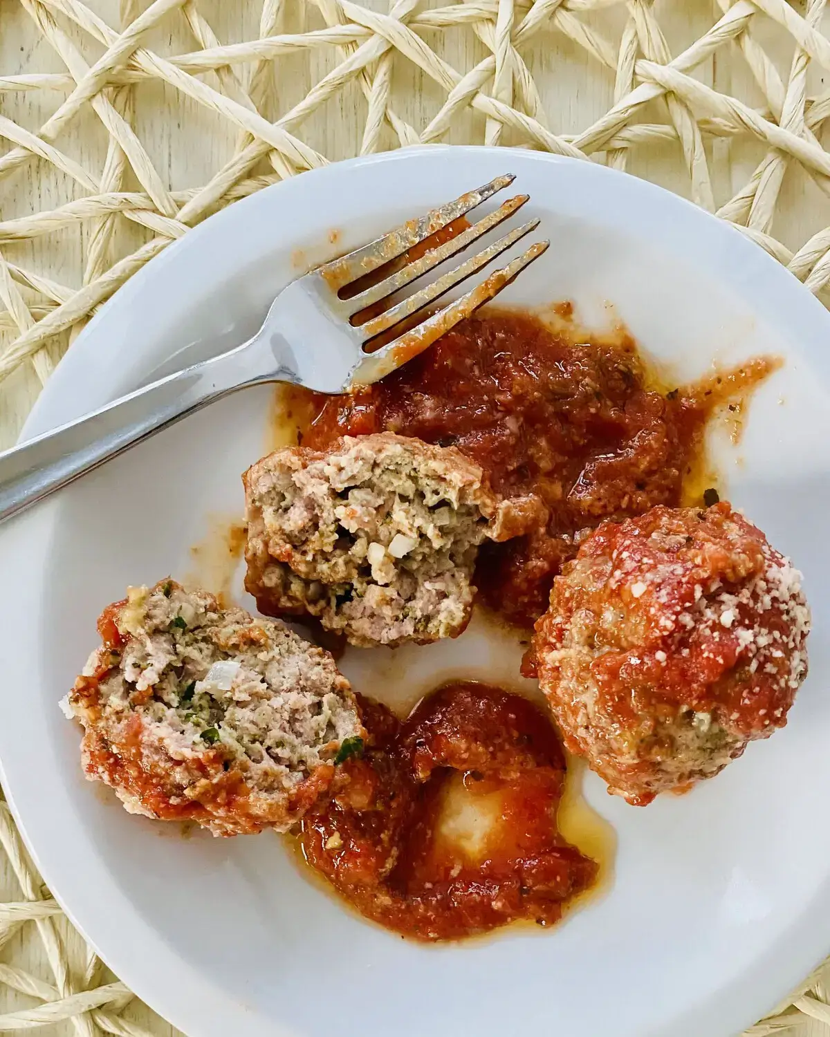 2 meatballs with marinara on a plate.
