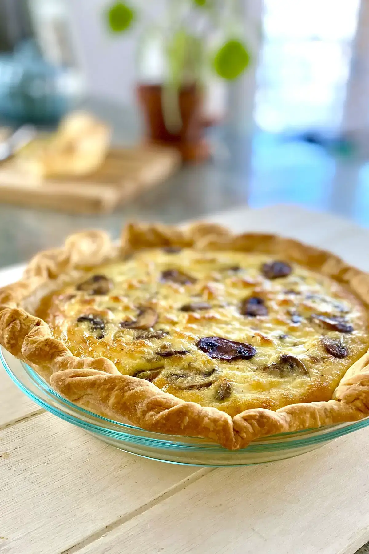 a whole mushroom quiche on a white board.