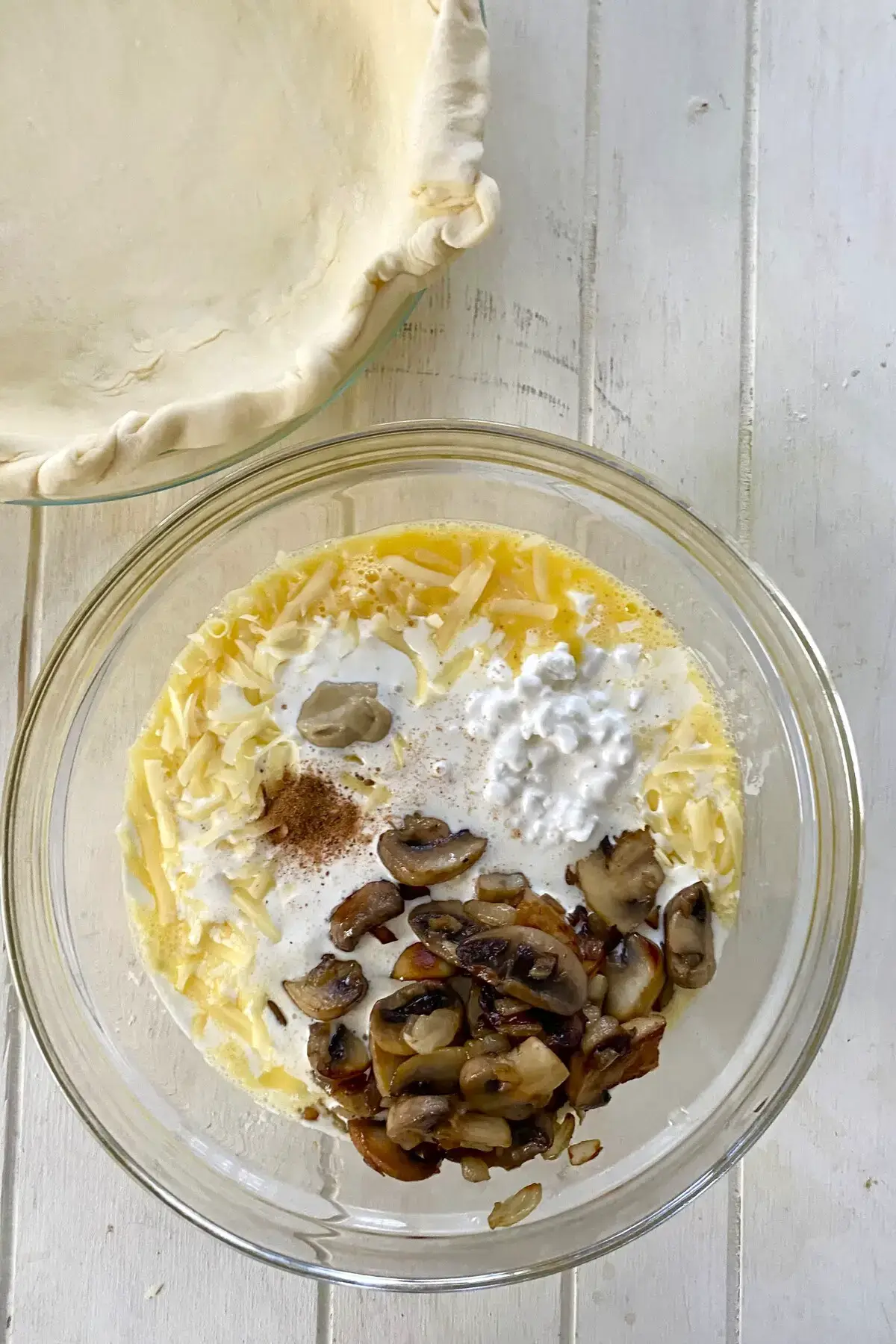 glass bowl with beaten eggs, cottage cheese, heavy cream, cheese, mustard, nutmeg, salt and pepper.