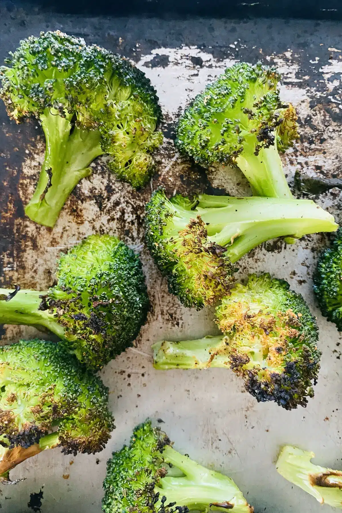closeup of broiled broccoli on a baking sheet.