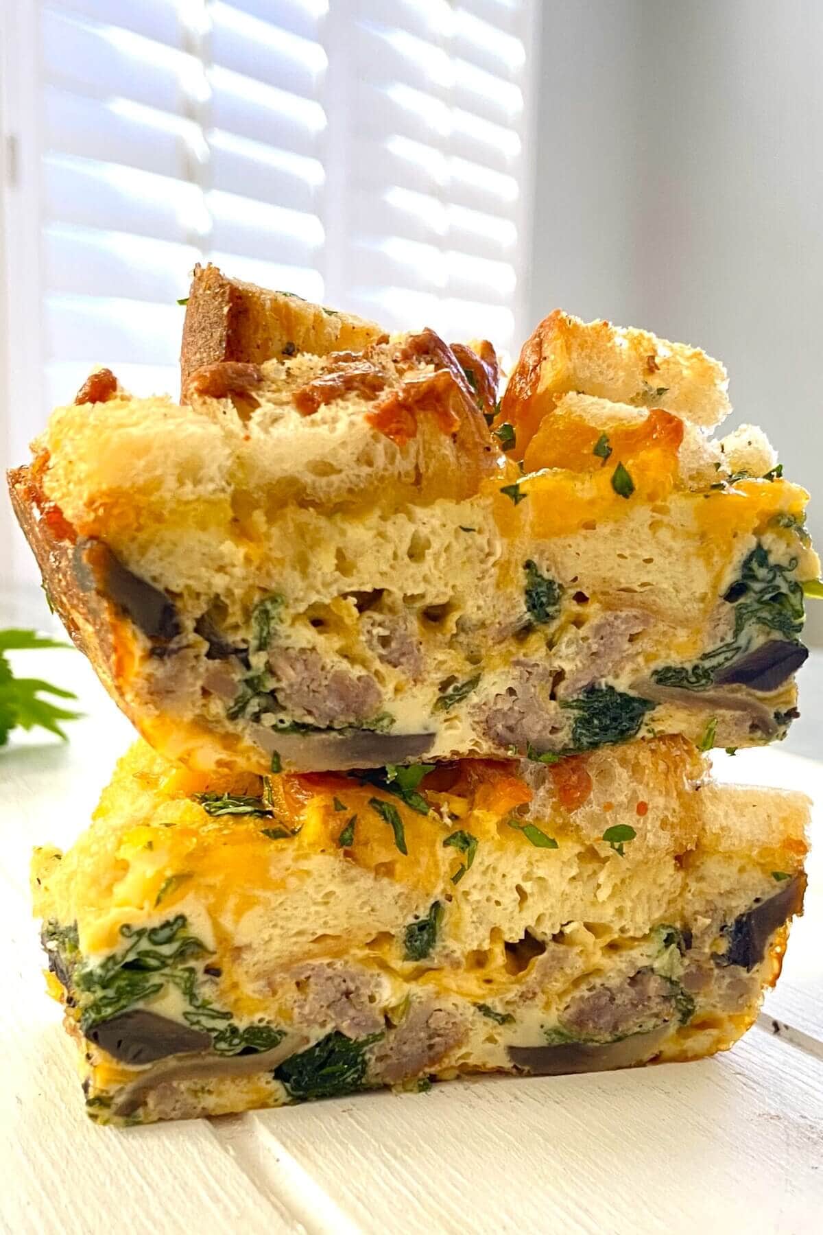 2 slices of egg casserole with croutons stacked on top of each other.
