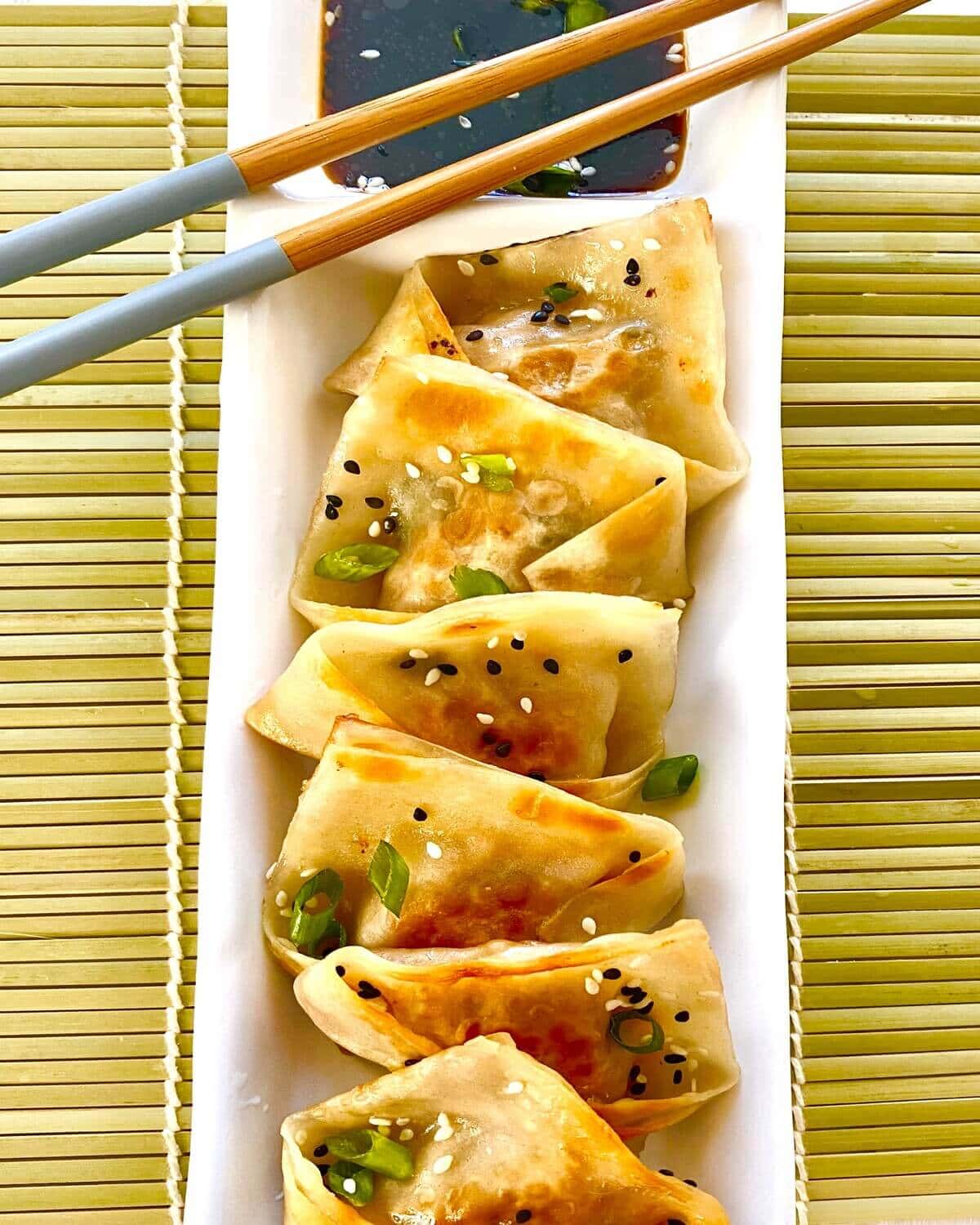 Pork potstickers on plate with chopsticks.
