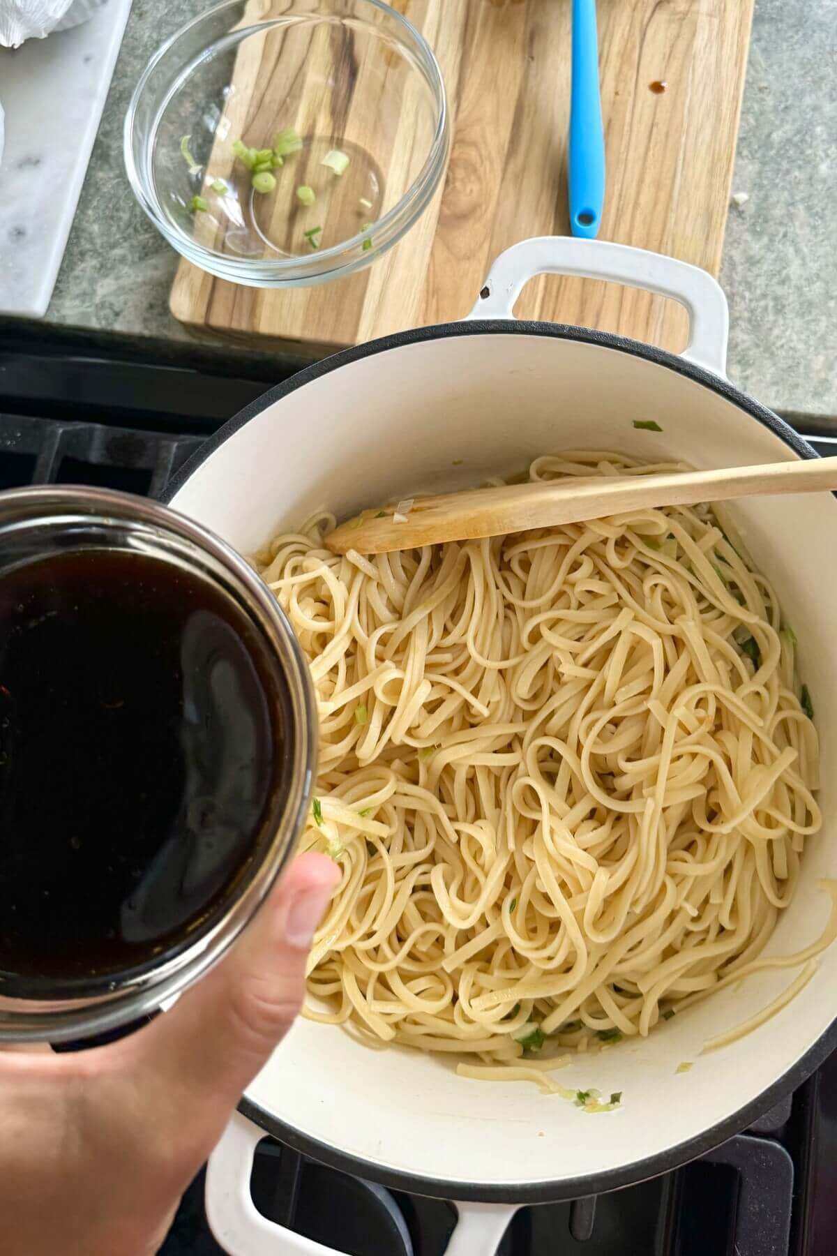 adding sauce to sesame noodles.