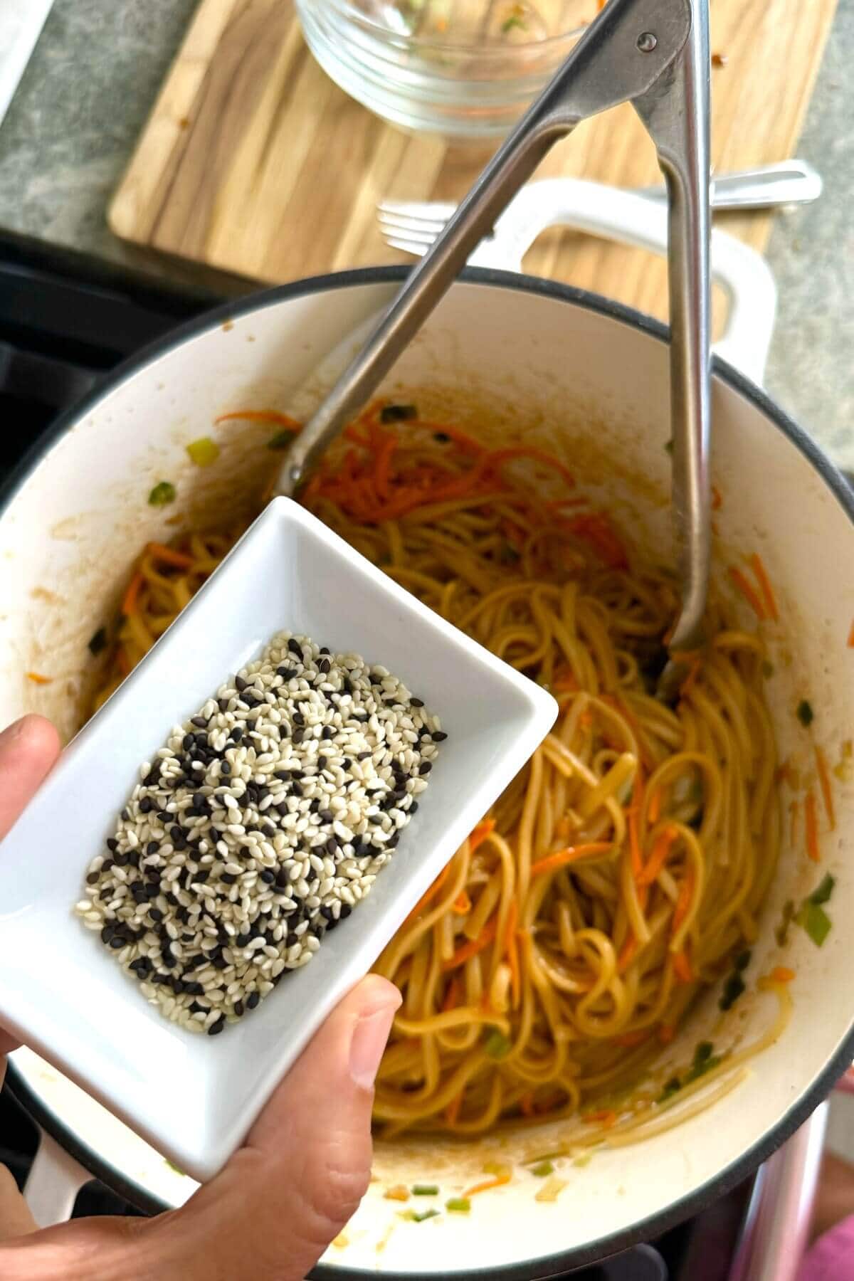 adding sesame seeds to noodles.