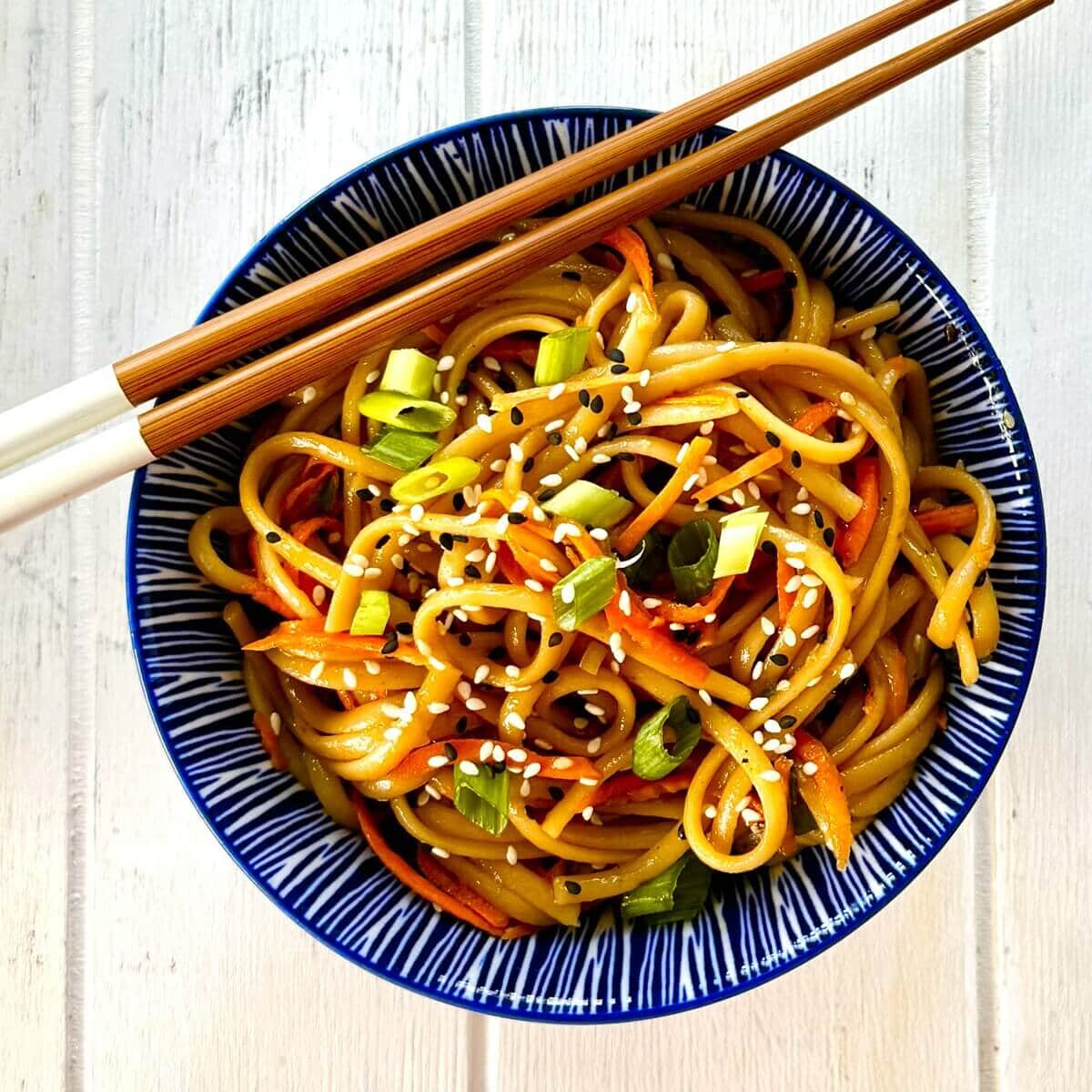 serving of sesame noodles with chopsticks.