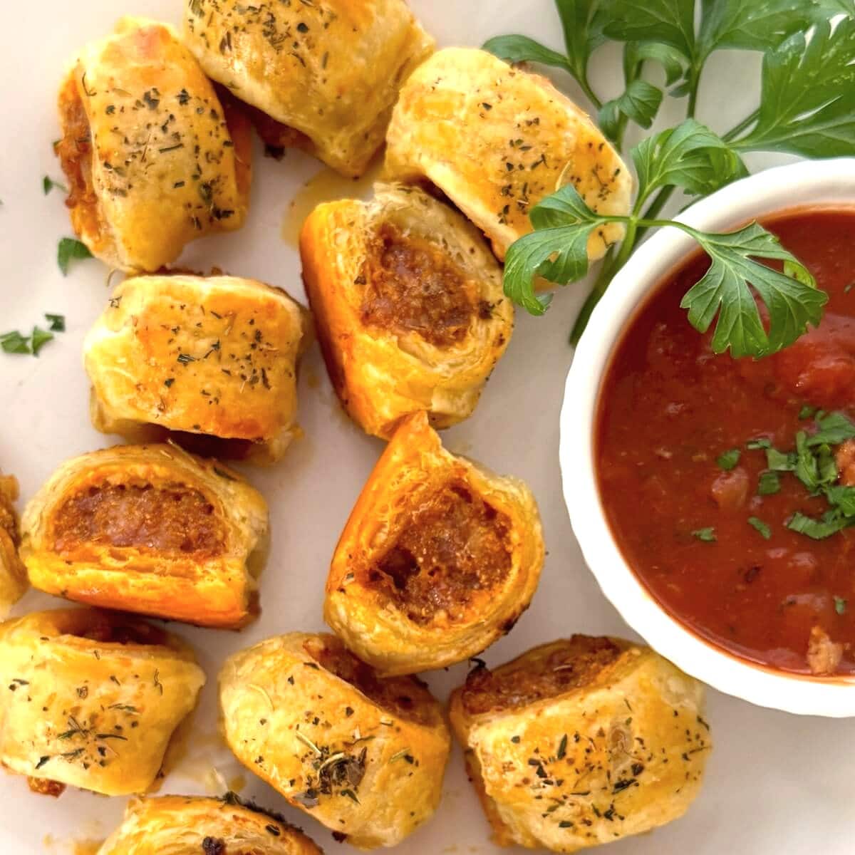 Italian sausage rolls on a plate with sauce.