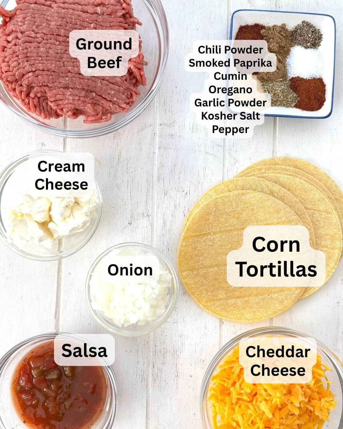 Ground beef, tortillas, spices, onion, cream cheese, cheese, and salsa on a board.