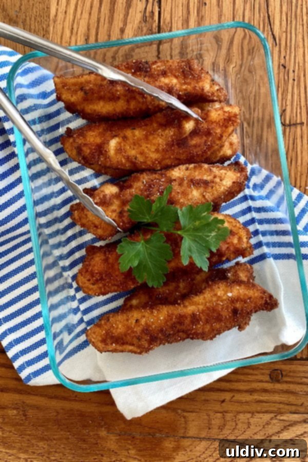 Southern Buttermilk Fried Chicken Tenders 2 Crispy Buttermilk Fried Chicken Tenders in a glass storage dish, ready to be served.