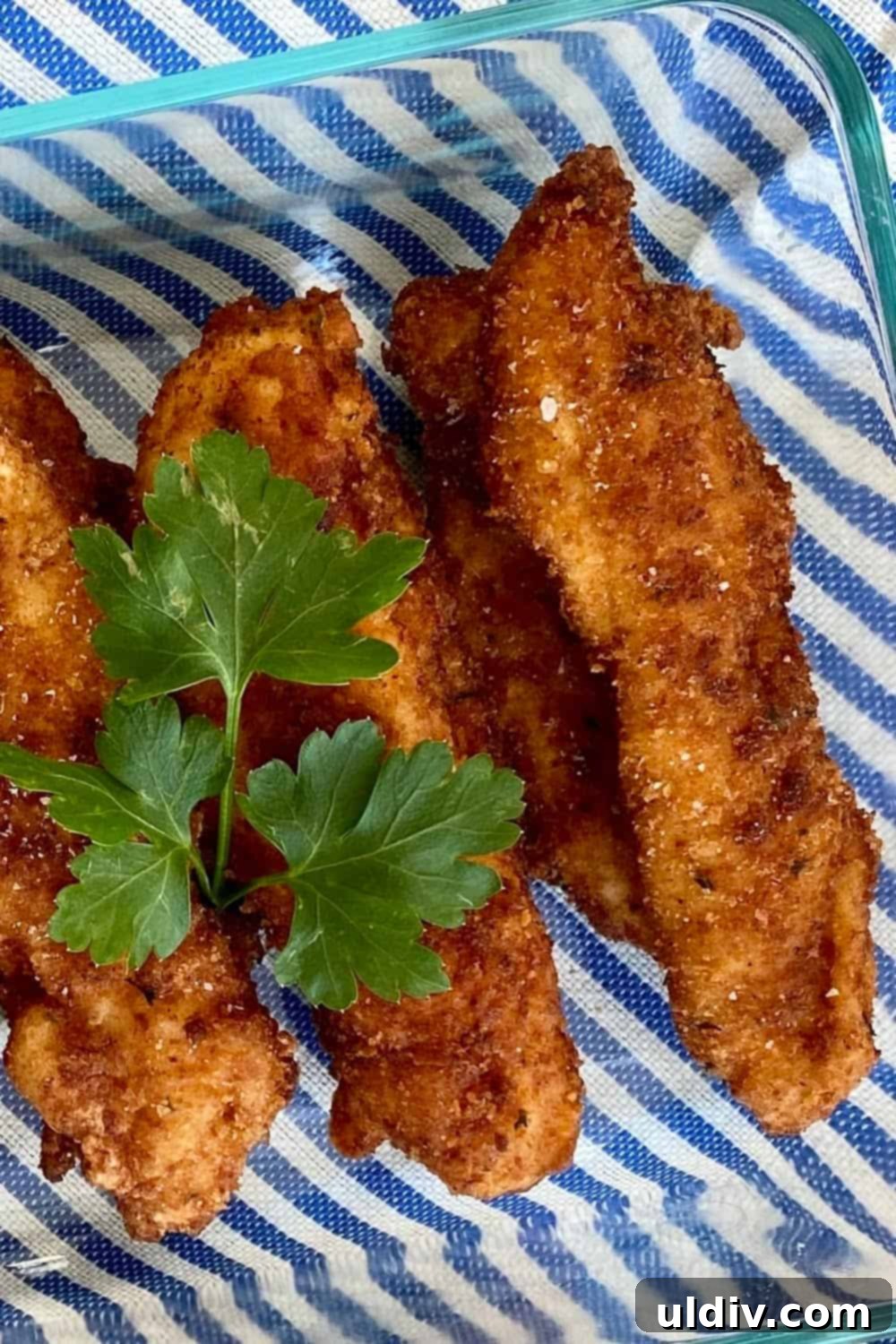 Southern Buttermilk Fried Chicken Tenders 5 A vibrant display of buttermilk fried chicken tenders on a stylish striped mat, emphasizing their golden crispness.