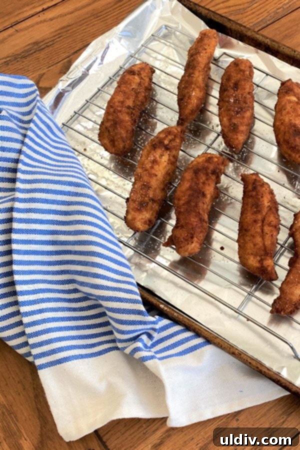 Southern Buttermilk Fried Chicken Tenders 6 A baking rack laden with freshly fried buttermilk chicken tenders, perfect for draining excess oil.