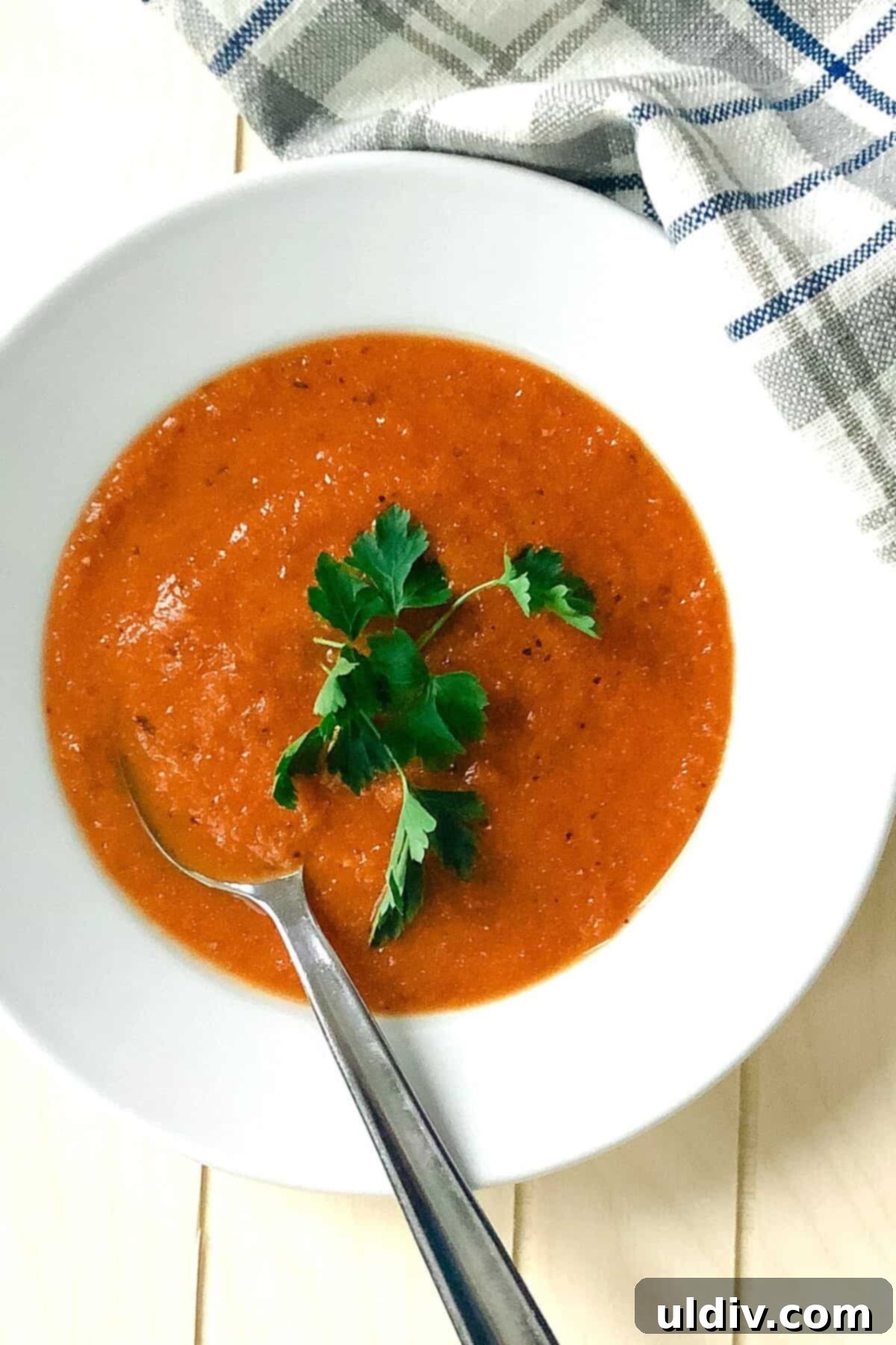 Basil-Kissed Tomato Bisque 2 Bowl of creamy roasted tomato basil soup with a spoon in it.