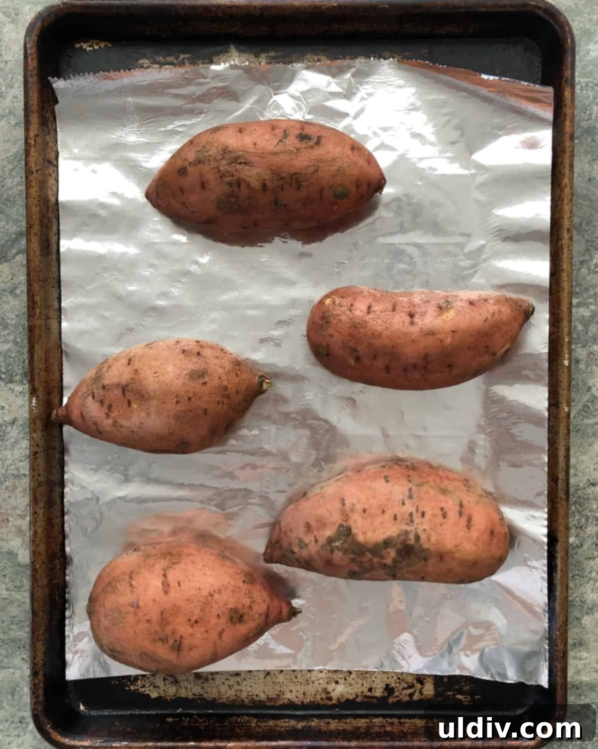 Tropical Vegan Coconut Stuffed Sweet Potatoes 3 sweet potatoes on a foil lined baking sheet ready to be baked