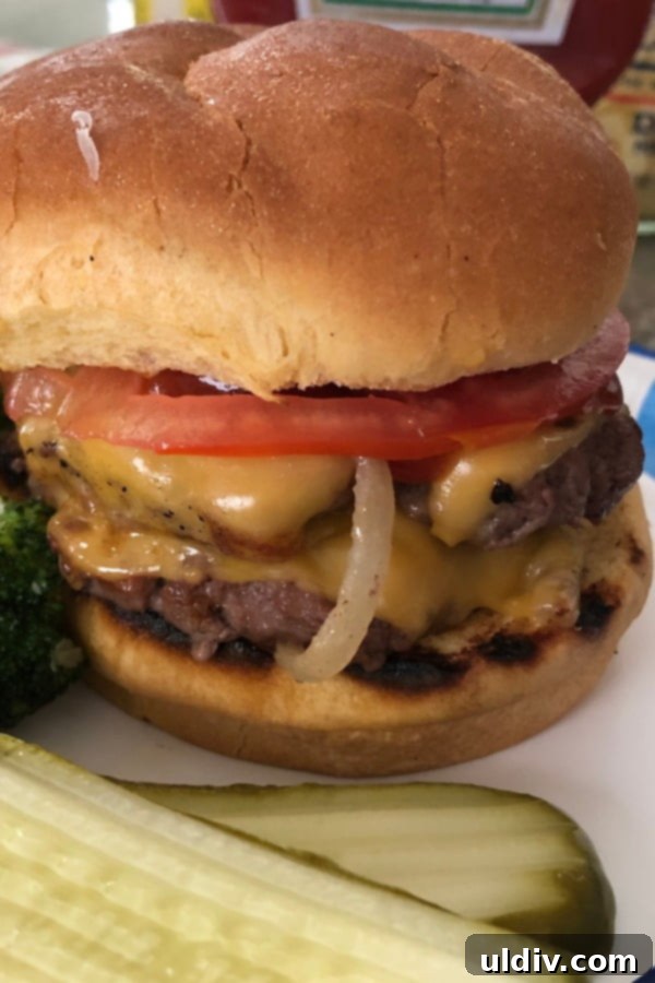 The Secret to Amazing Smash Burgers 9 Close-up of a smash burger topped with sliced tomato and pickles.