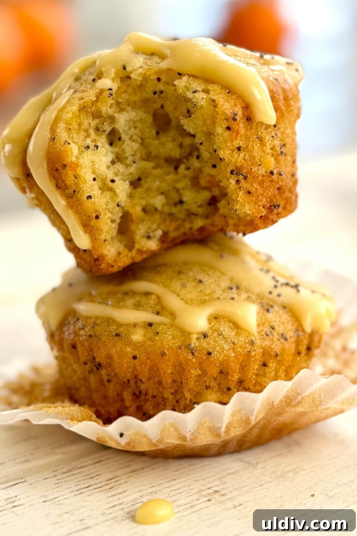 Sunshine Orange Poppy Muffins 2 Two glazed orange poppy seed muffins stacked against a warm background.