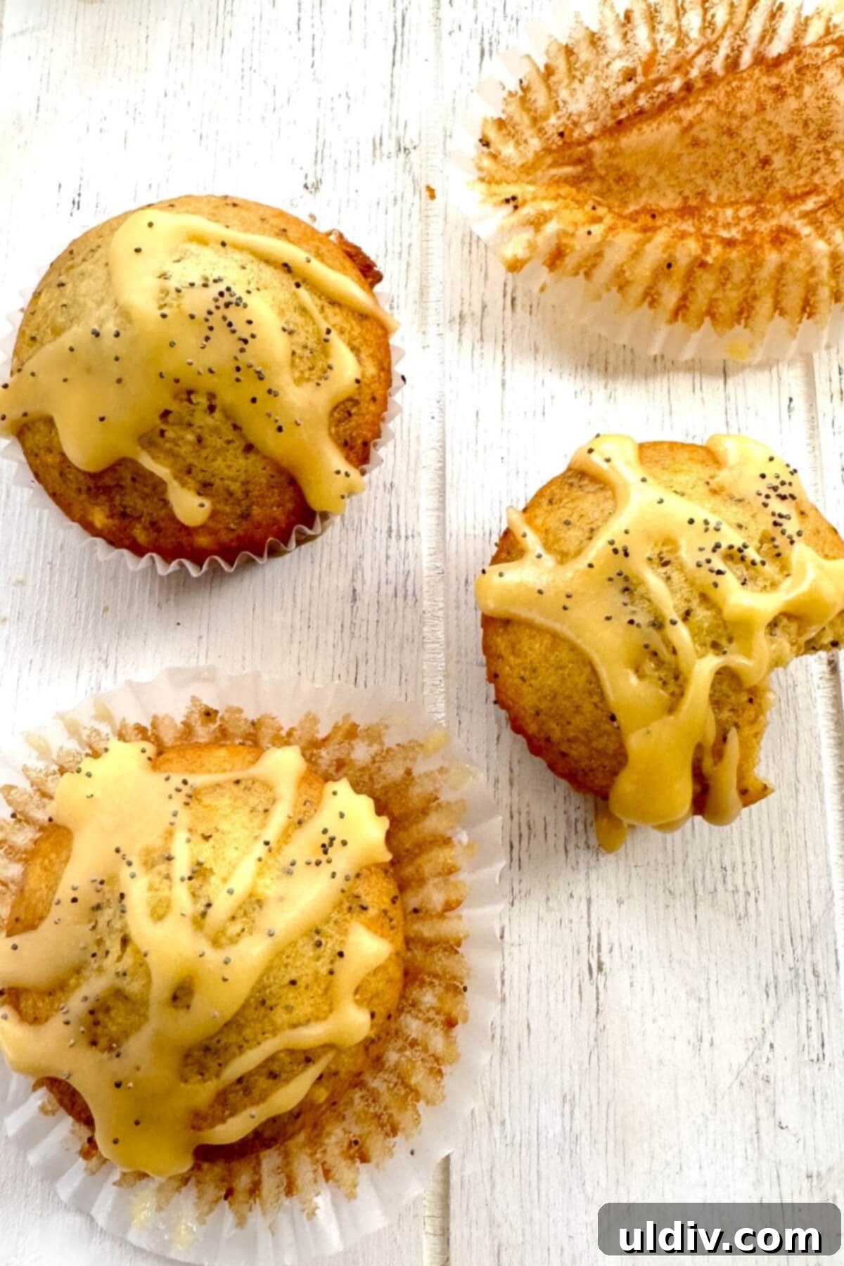 Sunshine Orange Poppy Seed Glaze Muffins 3 Four perfectly baked orange poppy seed muffins, with one showing a bite taken out, highlighting the moist interior.
