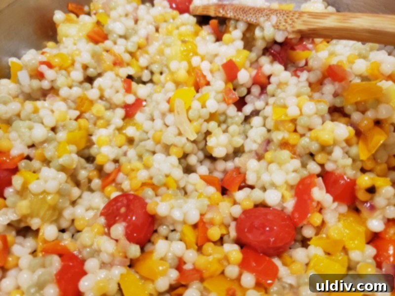 Evdeki Malzemelerle Yazlık Vegan Kuskus Salatası 7 Cooked couscous and sautéed vegetables gently mixed in a large bowl.