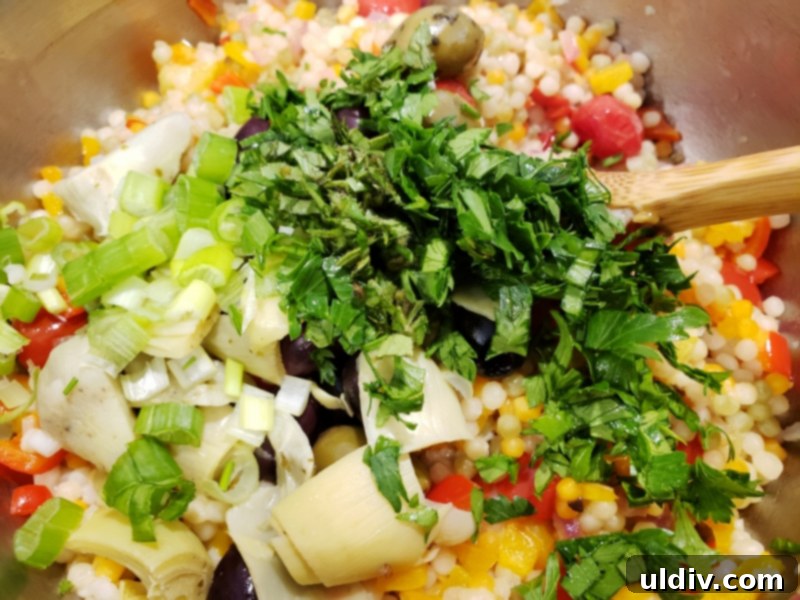 Evdeki Malzemelerle Yazlık Vegan Kuskus Salatası 9 Chopped green onion and fresh herbs being added to the salad ingredients.