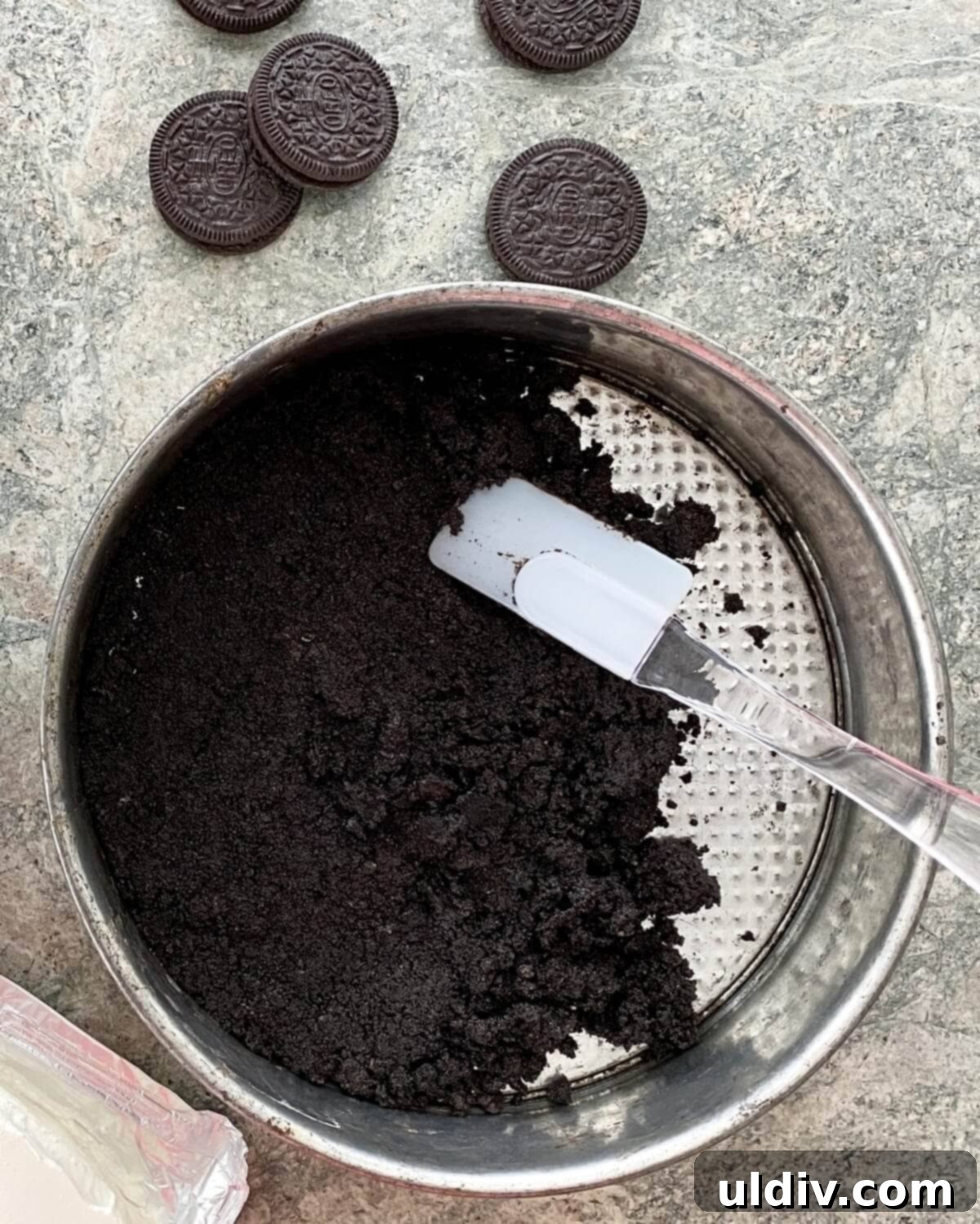 Effortless Oreo Cheesecake Recipe 5 Pressing the Oreo cookie crust mixture firmly into the base of a springform pan.