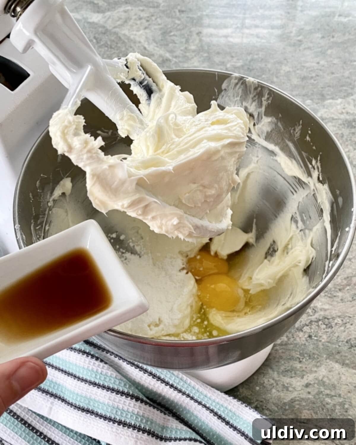 Effortless Oreo Cheesecake Recipe 6 Creamy cheesecake batter in a large mixing bowl with vanilla extract being added.