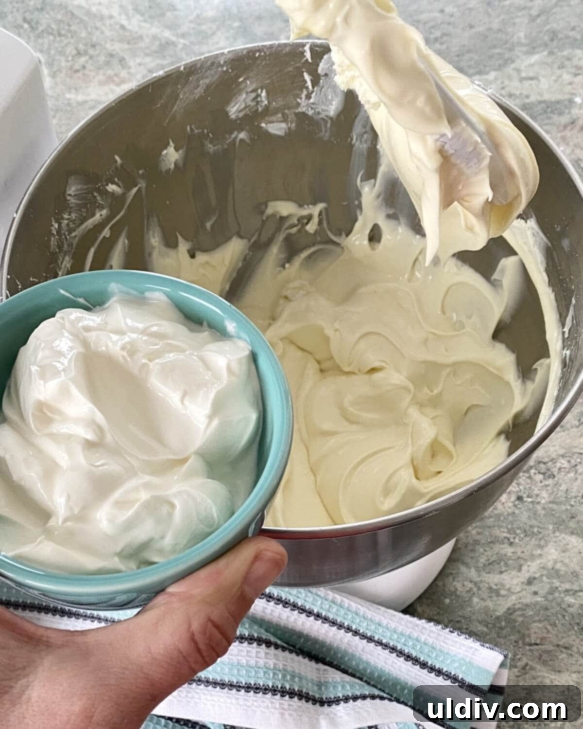 Quick and Easy Oreo Cheesecake 7 Sour cream being added to the cheesecake batter in a mixing bowl.