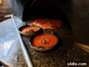 Etta A Taste of Hearth Magic 11 A cast iron baking dish filled with rich tomato sauce, ready for eggs to be cracked into it.