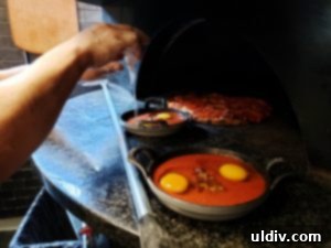 Etta A Taste of Hearth Magic 12 A chef cracking fresh eggs into the sauce-filled cast iron dishes, preparing them for the hearth oven.