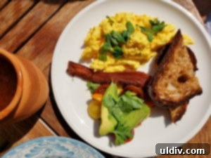 Etta A Taste of Hearth Magic 17 Soft scrambled eggs with cherry tomatoes, avocado, herbs, and crusty bread, presented as a fresh brunch option.